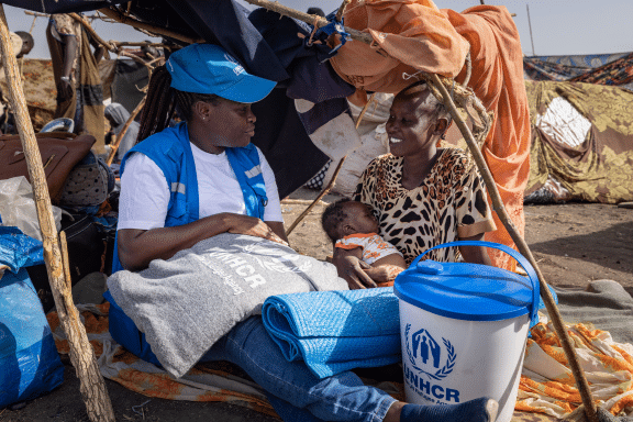 photo of UNHCR aid worker helping a mother and her baby
