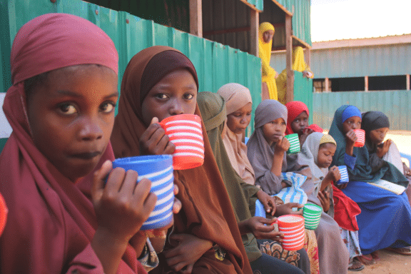A group of young people drinking from mugs in front of a building