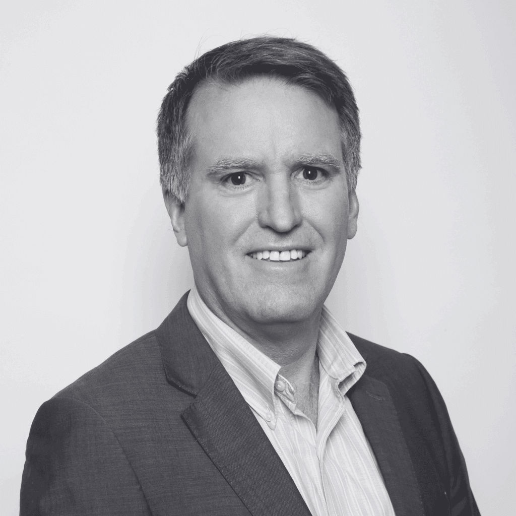 grayscale headshot of Adrian Graham who is smiling and wearing a shirt and jacket