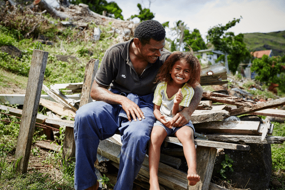 A photo of a father with his daughter sitting outside on a pike of wood