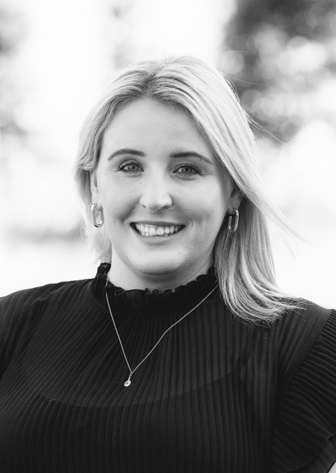 grayscale headshot of Jessica Barry who is smiling and has medium long blonde hair wearing a dark top