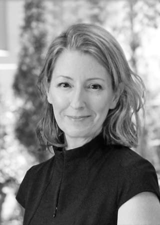 grayscale headshot of Kerren Morris who has medium long light wavy hair and wearing a black top