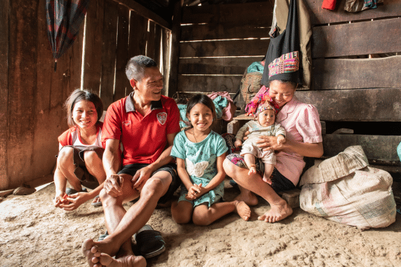 a photo of a family of two adults and three children sitting on the floor